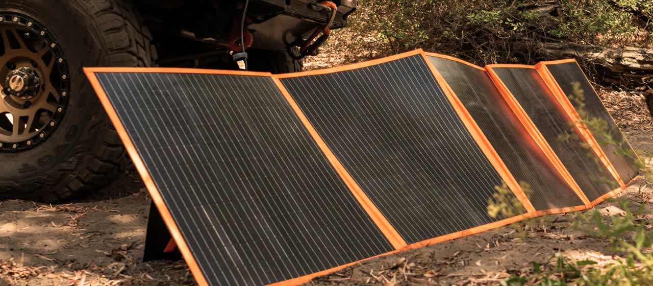 A solar blanket propped at an angle against a 4WD in bushland, catching the sun